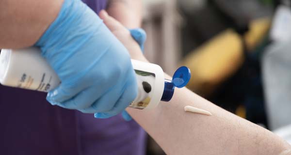 Staff member applying moisturising cream to arm