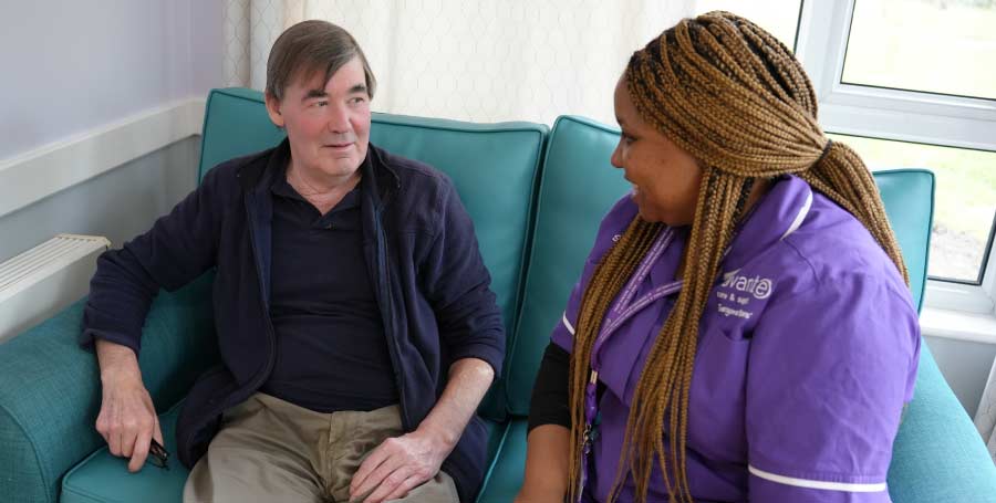 Carer and resident sitting on a sofa, talking