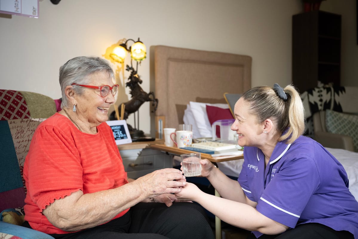 A carer and service user holding hands and talking to eachother