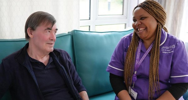 Resident and carer chatting on a sofa