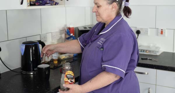 Home Carer preparing a drink in a service user kitchen