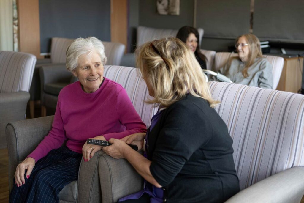Residents and Avante Carers sitting on lounge chairs talking and smiling