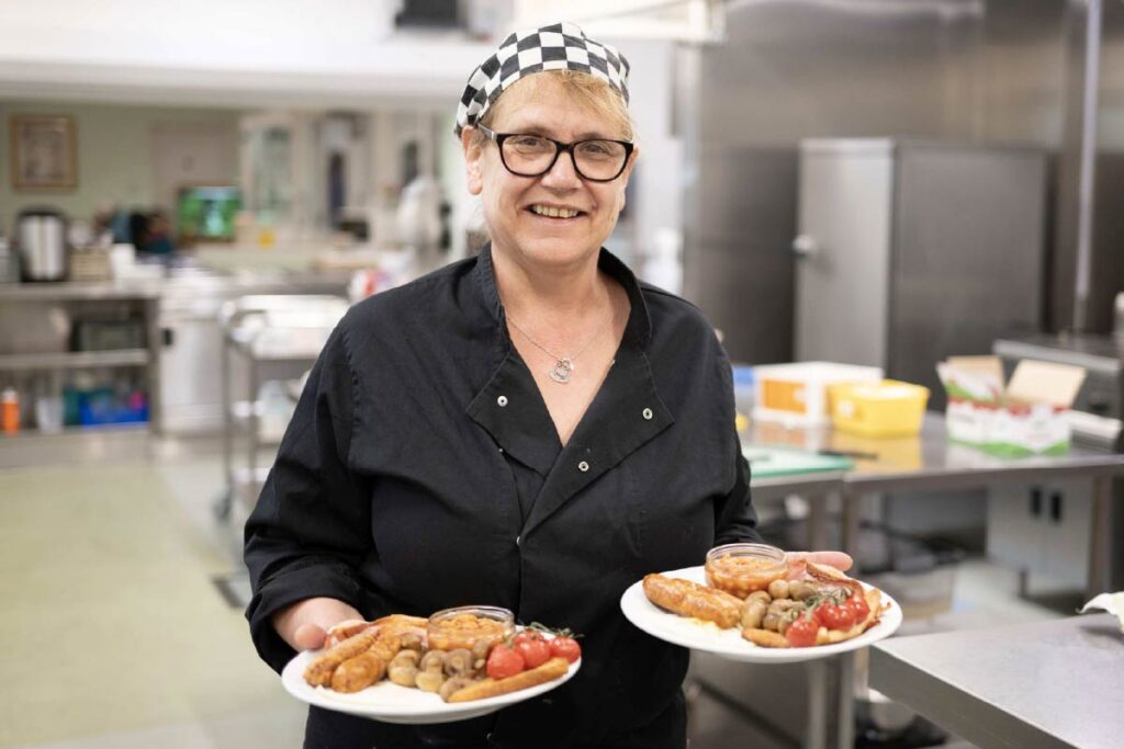 Avante Care Chef in a care home kitchen holding two plates of hot food