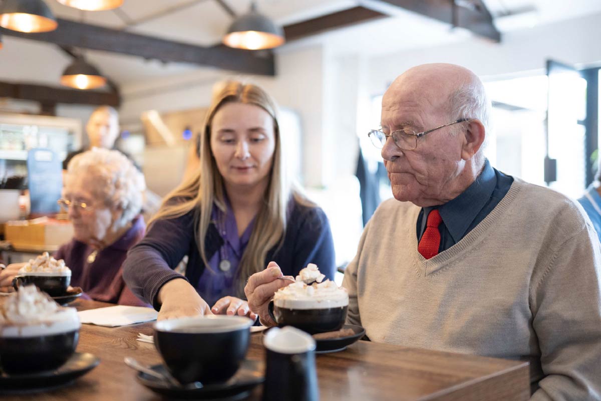 A resident and Avante Care Worker in a café enjoying a hot chocolate with cream