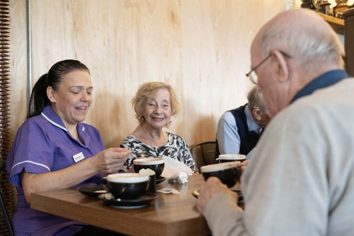 Residents and Avante Care staff sitting a coffee shop enjoying hot chocolate drinks
