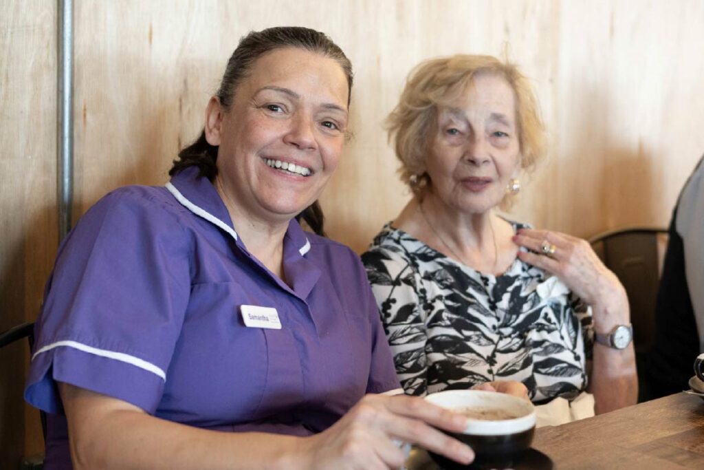 Resident and Avante Care staff sitting a coffee shop enjoying hot chocolate drinks