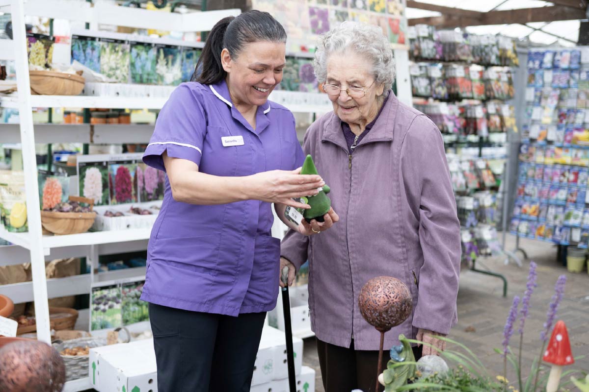 Resident and Avante Care Worker at a garden centre looking at seed and ornaments