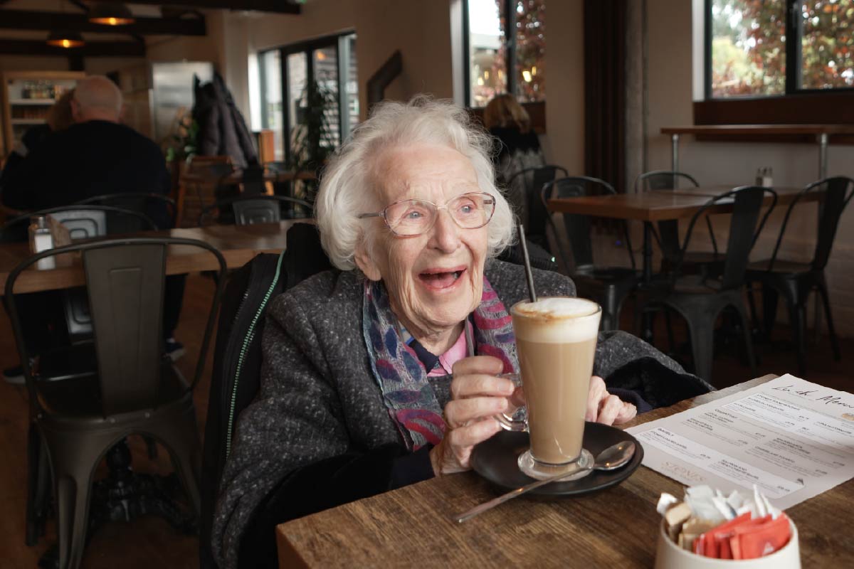 Service user smiling in a café drinking coffee