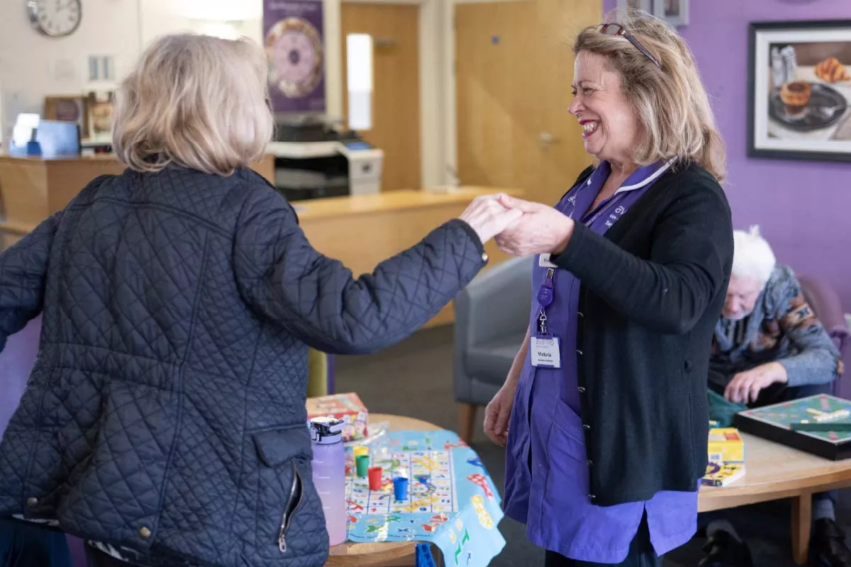 Avante Carer holding the hand of a resident and smiling