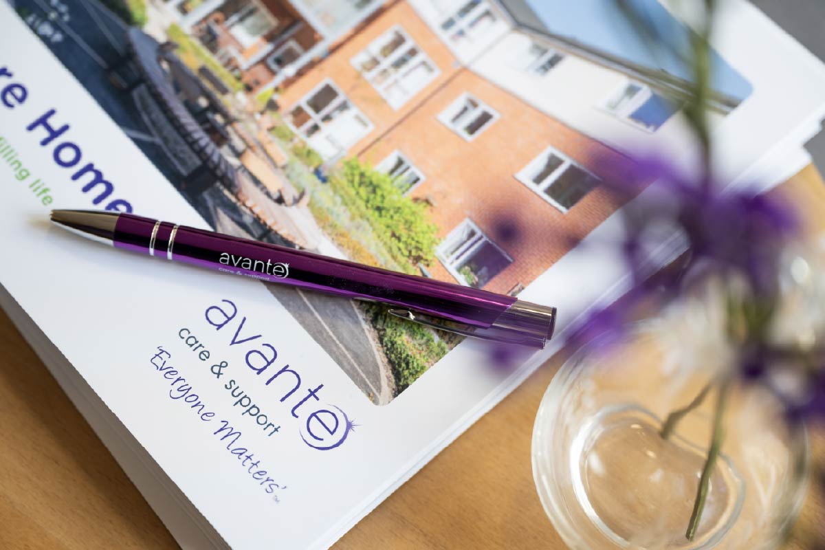 The front cover of a care home brochure with a pen laying on top