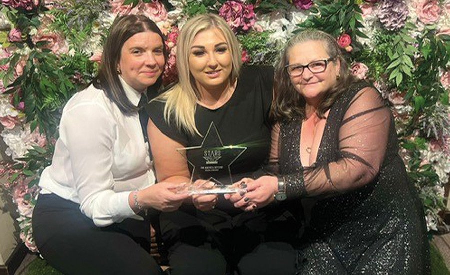 Three Home Care staff sitting and showing their award
