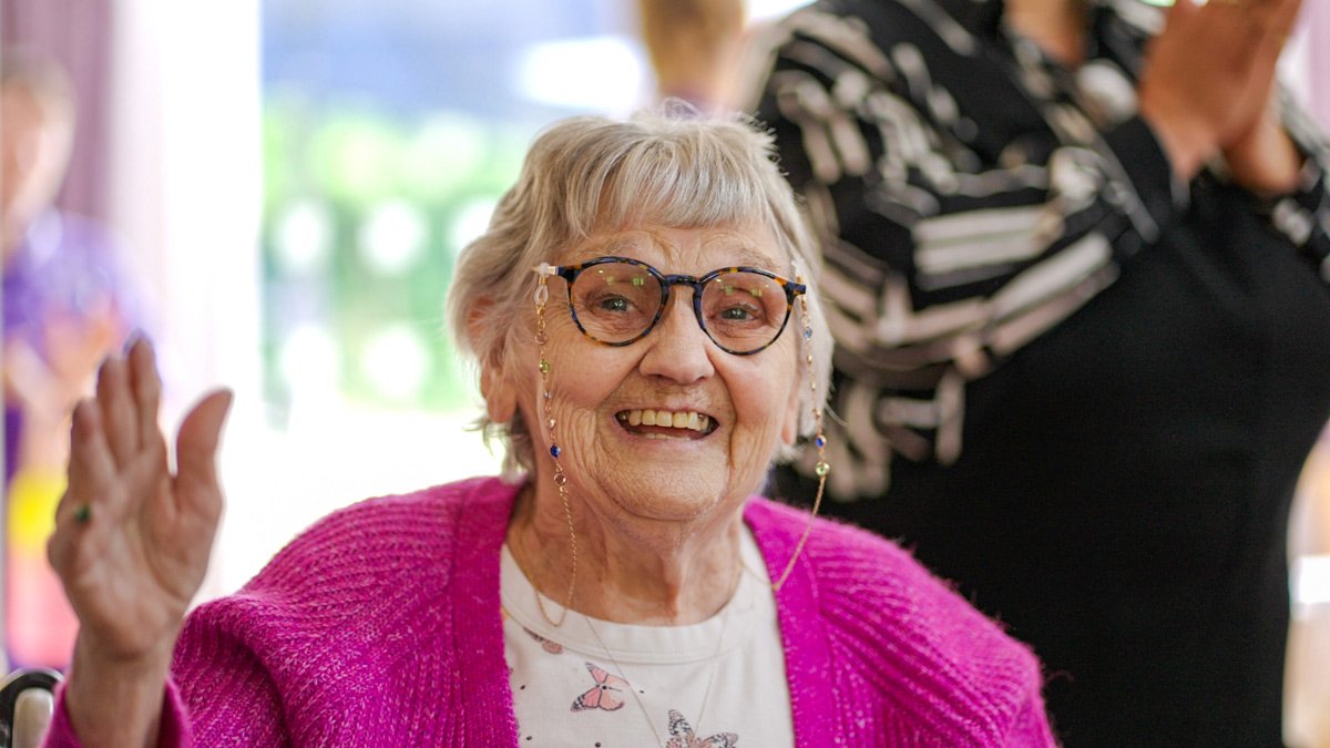 A resident smiling and waving
